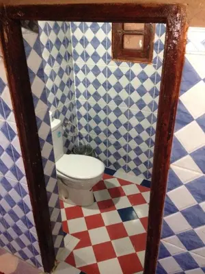 a bathroom with a toilet in a blue and white tiles at Chegaga Nomad Camp in El Gouera