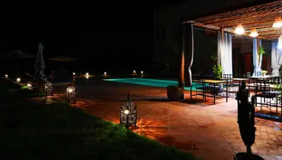 a patio with a swimming pool at night at Le petit Château des Anges in Marrakech
