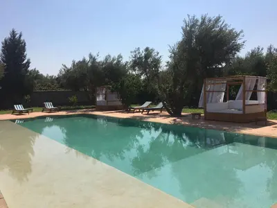 a swimming pool with two chairs and a gazebo at Le petit Château des Anges in Marrakech