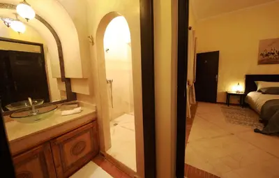 a bathroom with a sink and a bedroom with a bed at Le petit Château des Anges in Marrakech