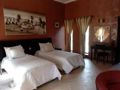 a hotel room with two beds and a piano at Le petit Château des Anges in Marrakech