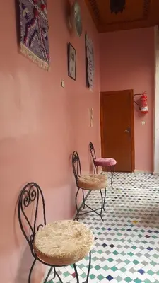 two chairs and tables in a room with pink walls at Riad amal in Fès