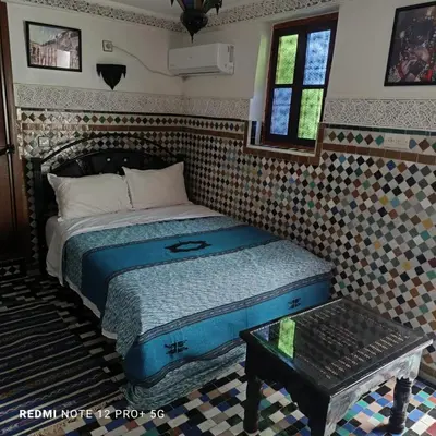 a small bedroom with a bed and a table at Riad amal in Fès