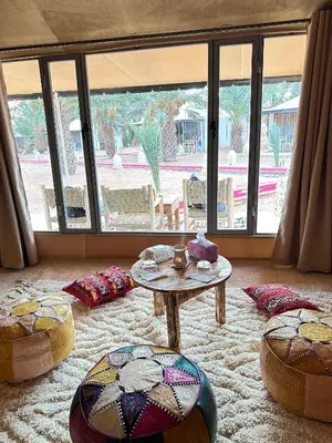 a living room with a table and some ottomans at Morocco Luxury Desert Camp in Merzouga