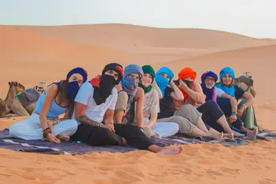 a group of people sitting in the desert at Morocco Luxury Desert Camp in Merzouga