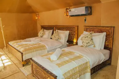a bedroom with two beds and a tv on the wall at Morocco Luxury Desert Camp in Merzouga