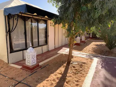 a small house with a tree in front of it at Tafouyte Luxury Camp in Merzouga