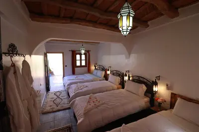 a bedroom with four beds and a chandelier at Maison d'Hôte Argana in Aït Idaïr