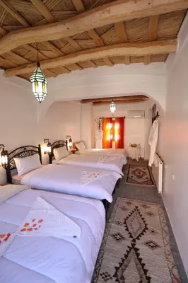 two beds in a room with wooden ceilings at Maison d'Hôte Argana in Aït Idaïr