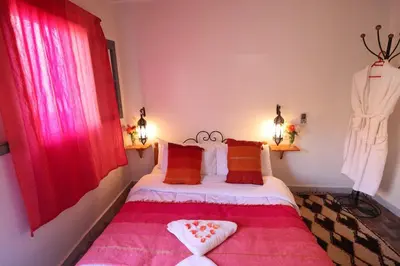 a bedroom with a bed with a red window at Maison d'Hôte Argana in Aït Idaïr