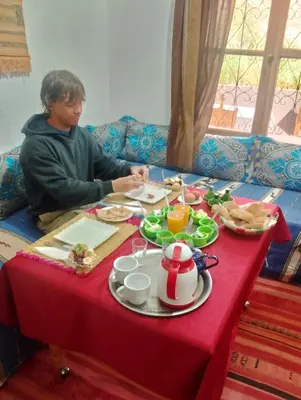 a woman sitting at a table with a red table cloth at Maison d'Hôte Argana in Aït Idaïr
