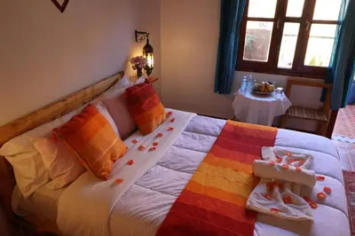 a bedroom with a large bed with colorful pillows at Maison d'Hôte Argana in Aït Idaïr