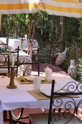 a table with a white table cloth and an umbrella at Maison d'Hôte Argana in Aït Idaïr