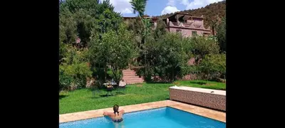 a woman sitting in a swimming pool in a house at Ourika Timalizène le jardin des délices in Tamzerdirt
