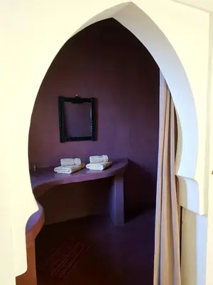 a room with a purple wall with a table with a mirror at Ourika Timalizène le jardin des délices in Tamzerdirt