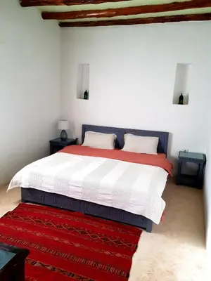 a bedroom with a large bed with a red rug at Ourika Timalizène le jardin des délices in Tamzerdirt