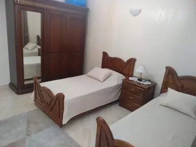 a bedroom with two beds and a dresser and a mirror at Apartment Centre Meknes in Meknès