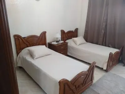 two twin beds in a room with a night stand at Apartment Centre Meknes in Meknès