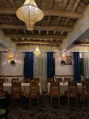 a dining room with tables and chairs and a chandelier at Hôtel Bia Besta in Boumalne