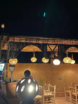 a restaurant with chairs and lights and a bridge at Hôtel Bia Besta in Boumalne