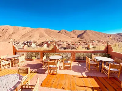 a deck with tables and chairs and a view of the desert at Hôtel Bia Besta in Boumalne