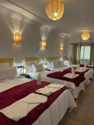 a hotel room with three beds with red and white sheets at Hôtel Bia Besta in Boumalne