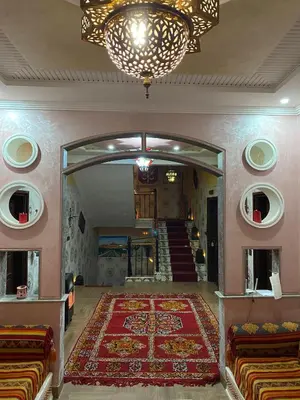 a hallway with a red rug and a chandelier at Hôtel Bia Besta in Boumalne