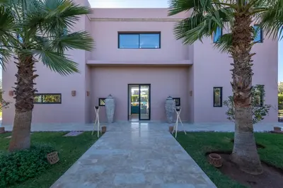 a building with two palm trees in front of it at Les Iris - Peaceful villa with heated private pool & hammam in Marrakech