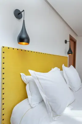 a bed with white pillows and a yellow headboard at Les Iris - Peaceful villa with heated private pool & hammam in Marrakech