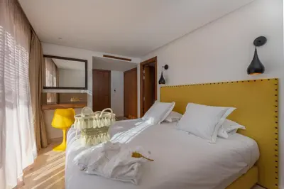 a bedroom with a white bed with a yellow headboard at Les Iris - Peaceful villa with heated private pool & hammam in Marrakech