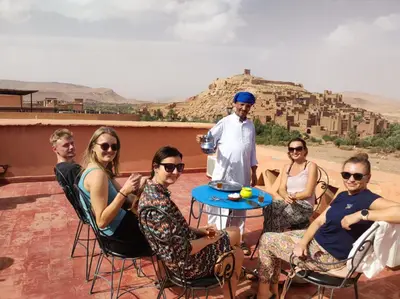 a group of people sitting around a table on a roof at La Fibule D'or in Aït Ben Haddou