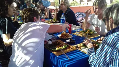 a group of people sitting around a table eating food at La Fibule D'or in Aït Ben Haddou