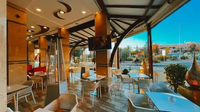 a restaurant with tables and chairs and a large window at Residence Chay - Luxury Appart in Ouarzazate
