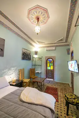 a bedroom with a bed and a table and a window at Riad Noha in Fès