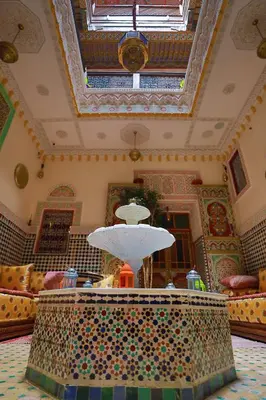 a large room with a ceiling and a table with a light at Riad Noha in Fès