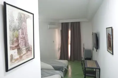 a hotel room with two beds and a picture on the wall at Hotel Nouzha in Fès