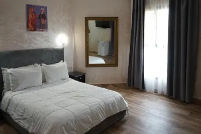 a bedroom with a white bed and a mirror at Hotel Nouzha in Fès
