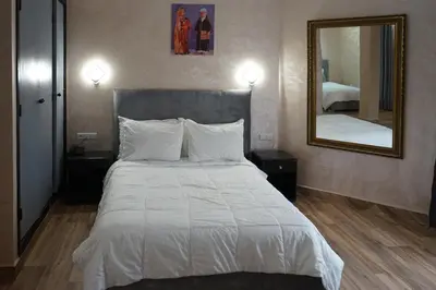 a bedroom with a large white bed with a mirror at Hotel Nouzha in Fès