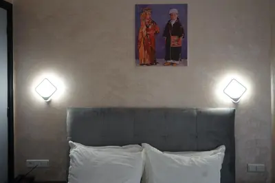 two lights above a bed with a picture on the wall at Hotel Nouzha in Fès