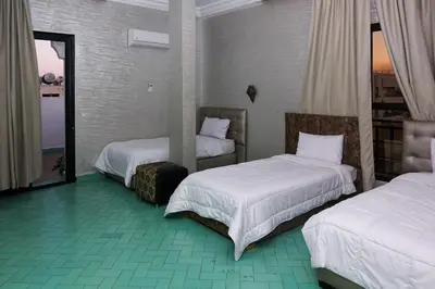 a hotel room with two beds and a mirror at Hotel Nouzha in Fès