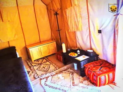 a room with a bed and a table in a room at Camel Luxury Camp in Merzouga