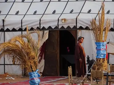 a man standing outside of a tent with a door at Camel Luxury Camp in Merzouga