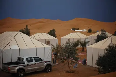 a truck parked in front of tents in the desert at Camel Luxury Camp in Merzouga