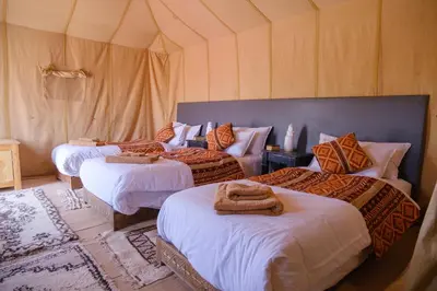 a room with three beds in a tent at Camel Luxury Camp in Merzouga