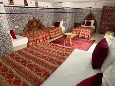 a bedroom with two beds and a rug at Riad Hadia Fes - Prestige Stay in Fès