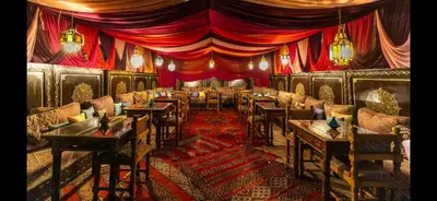 a restaurant with tables and chairs and red curtains at Riad Hadia Fes - Prestige Stay in Fès