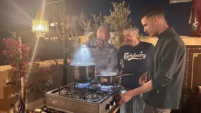 three men standing around a stove with pots on it at Riad Hadia Fes - Prestige Stay in Fès