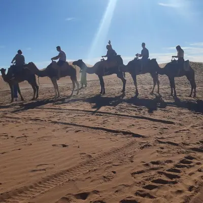 a group of people riding horses in the desert at Camp Mhamid Sahara Tours in Mhamid