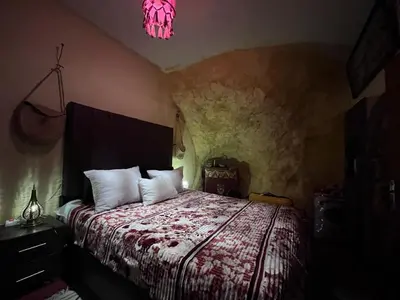 a bedroom with a bed and a pink light at Grotte Thami in Bhalil