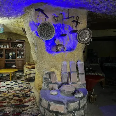 a living room with a fake tree and a couch at Grotte Thami in Bhalil